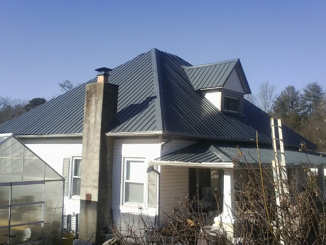 Dark blue standing seam metal roof on a white farmhouse with dormer — Slate & Tile Roof Repair by Roofing Brothers in Aliso Viejo