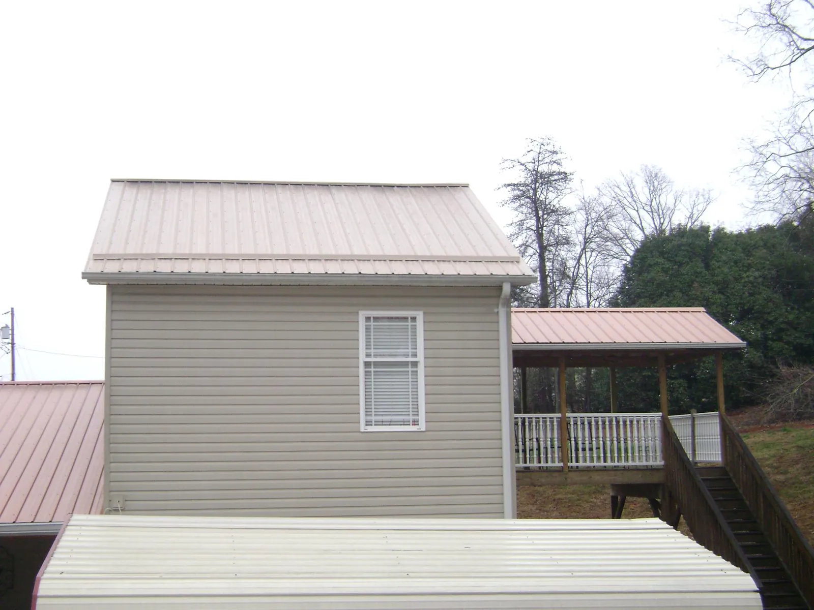 Tan metal roofs on a two story addition and attached porch, from a Roof Replacement job in Aliso Viejo