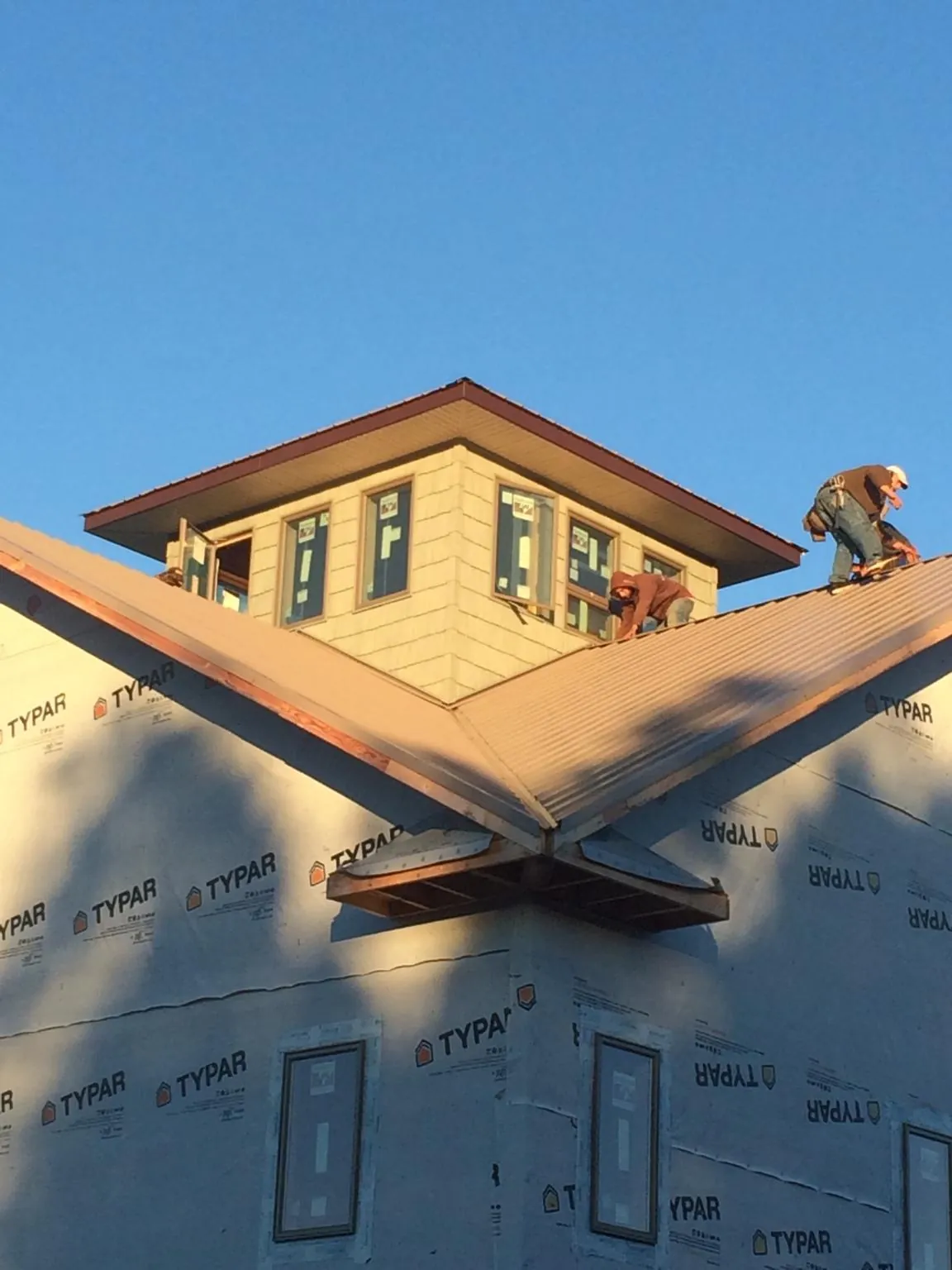 Roofers working around a rooftop cupola on a new metal roof at sunset — Roof Waterproofing in Aliso Viejo by Roofing Brothers